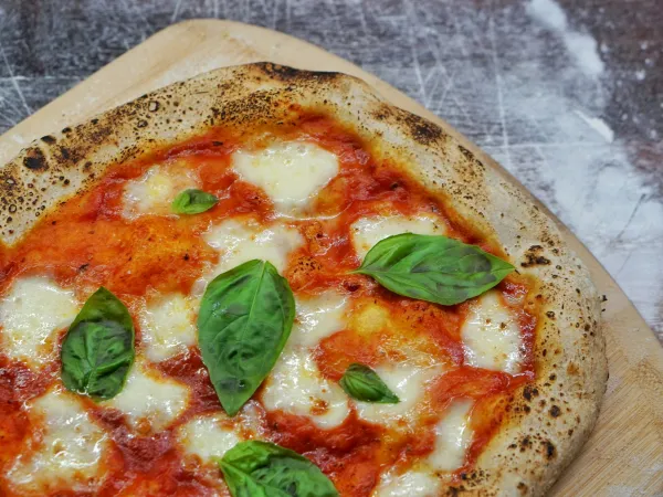 Margherita pizza with fresh basil on a wooden peel
